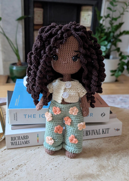 Crocheted doll with floral pants.