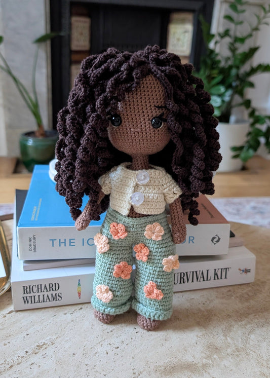 Crocheted doll with floral pants.